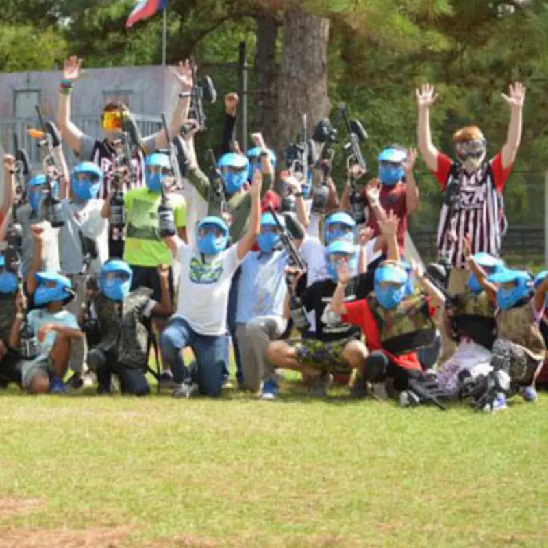 people raising their hands while playing paintball