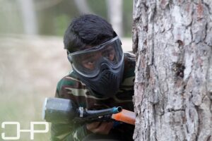 guy hiding behind tree during paintball game