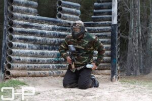 man kneeling down while playing paintball