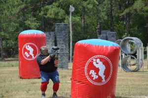 man hiding and shooting during paintball game
