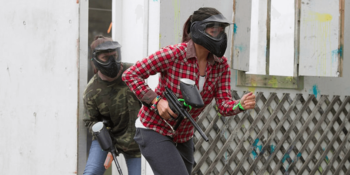 women hiding and running during paintball game
